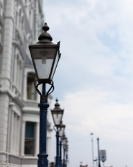 Fototapeta na wymiar Light post on the road. Street light post. Street lamp on the road. Cast iron street lamp. Designer lamp post. Lamps on the top of lamppost. Street road light.