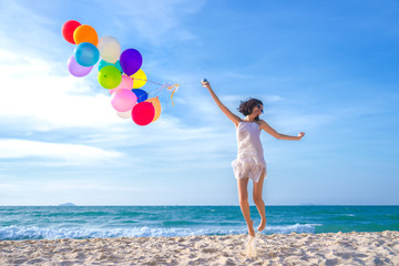 Beauty girl smiling and jumping on the beach at the day time. with colorful air balloons Very much.