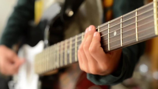A boy is playing the electric guitar