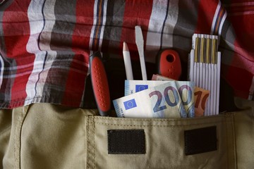 Handwerker mit Werkzeug und Geldscheinen in der Hosentasche