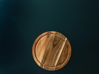 Round wood cutting board on the black background. Copy-space for your text. Top view. Flat layot