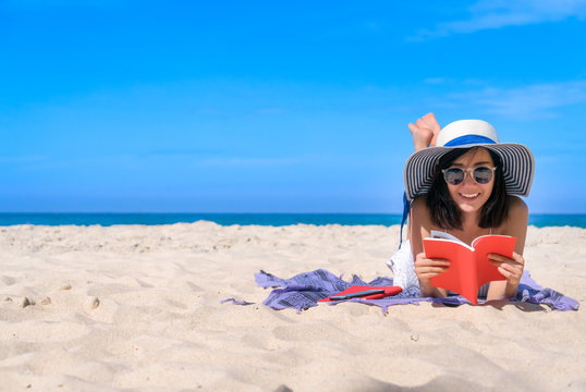 Woman happy smiling and read books on the beach on the beach on a beautiful . Pretty girl asian in casual looking away and smile , laughing. The beach beautiful at bright sky