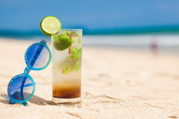 delicious mojito cocktail and pink sunglasses by the beach