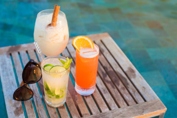 three perfect cocktails pina colada, sex on the beach and mojito, pool background