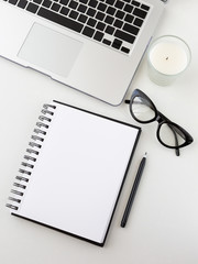 Feminine home office table desk frame. Laptop, notepan and pen, aromatic candle and cat eyewear....