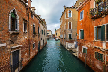 View of the street canal in Venice, Italy. Colorful facades of old Venice houses. Venice is a popular tourist destination of Europe. Venice, Italy.