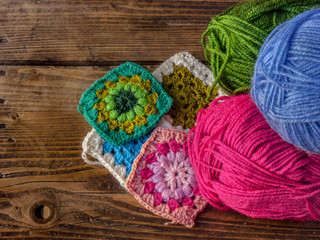 colorful wool and granny square on a wooden background