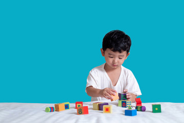 3 years old little cute Asian boy play toy or square block puzzle at home on the bed, kid lying...