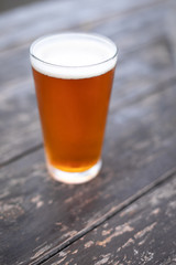 Close up on the foamy head of a pint of beer on a wood table
