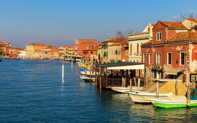 Obraz premium Street canal in Murano island, Venice. Narrow canal among old colorful brick houses in Murano, Venice. Murano postcard, Venice, Italy.