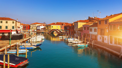 Obraz na płótnie Canvas Street canal in Murano island, Venice. Narrow canal among old colorful brick houses in Murano, Venice. Murano postcard, Venice, Italy.