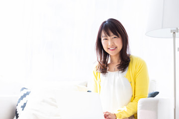 部屋でパソコンを見るミドル女性