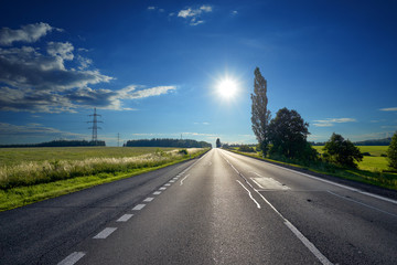 Glowing sun over an empty asphalt road in rural countryside