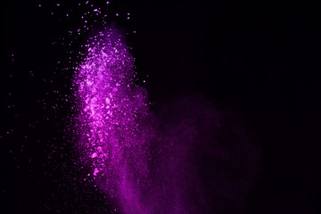 Freeze motion of purple color powder exploding on black background.
