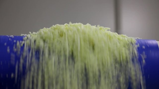 Grated cheese pouring off the end of a conveyor