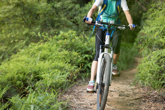 woman cyclist riding mountain bike on forest  trail