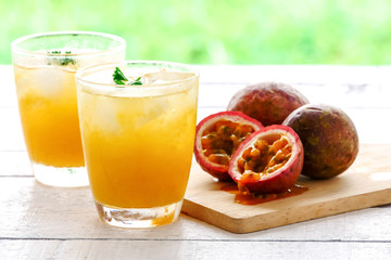 A glass of juice and fresh passion fruit on wooden table
