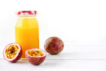 A bottle of juice and fresh passion fruit on wooden table. copy space