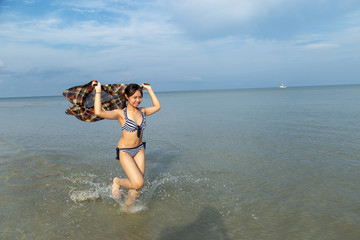 Teenage wearing bikini running at the beach by the sea.