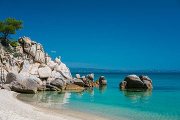 Tropical sandy beach with large rocks and blue sea