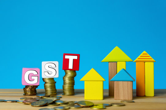 GST for properties. Building from wood cubes stacking with gold coin. Tax, taxation, property and investment concept or other your content.