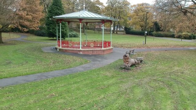Moving away from a Victorian bandstand to an aerial shot above trees.