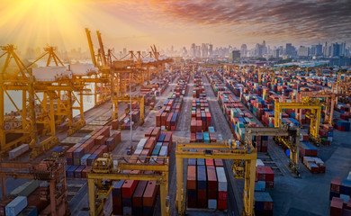 Naklejka premium Logistics and transportation of Container Cargo ship and Cargo plane with working crane bridge in shipyard at sunrise, logistic import export and transport industry background