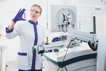 Modern laboratory. Competent blonde keeping smile on her face while standing near her equipment