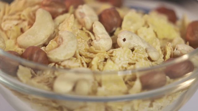 Rotating corn flakes with nuts in a glass bowl