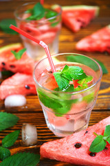 summer refreshing cocktail of watermelon, green mint and ice water on a wooden background in a glass with frost