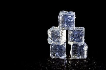 ice cubes reflection on black table background.