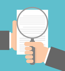 Hand holding magnifying glass over a document