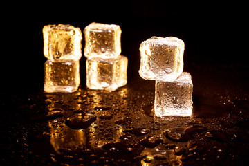 Golden ice cubes on black background.
