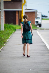 Girl with black backpack going to school. Back view.