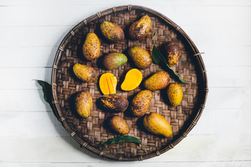 Nature mango In threshing basket On a wooden table and a white cloth