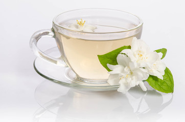 Obraz na płótnie Canvas Glass cup of Tea with jasmine flowers and leaves