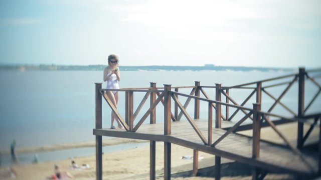 Hot girl standing on the beach on the bridge in the sun. 4k.