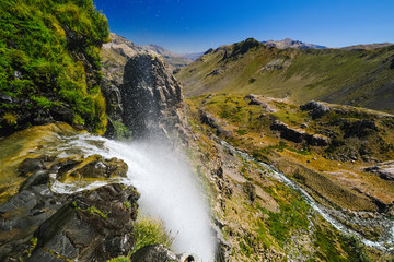 a waterfall in the middle of the green mountains