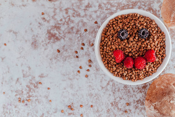 Smile from blackberries and raspberries in a plate with buckwheat and rolls.