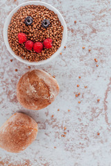 Smile from blackberries and raspberries in a plate with buckwheat and rolls.