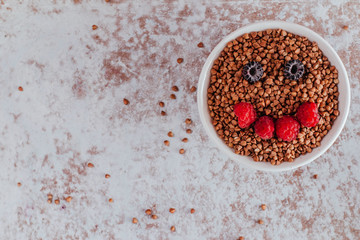 Smile from blackberries and raspberries in a plate with buckwheat and rolls.