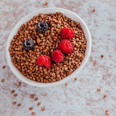Smile from blackberries and raspberries in a plate with buckwheat and rolls.