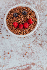 Smile from blackberries and raspberries in a plate with buckwheat and rolls.