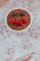 Smile from blackberries and raspberries in a plate with buckwheat and rolls.