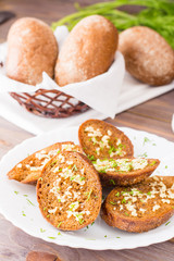 Fresh rye garlic croutons with dill on a plate and buns in a basket on a wooden table