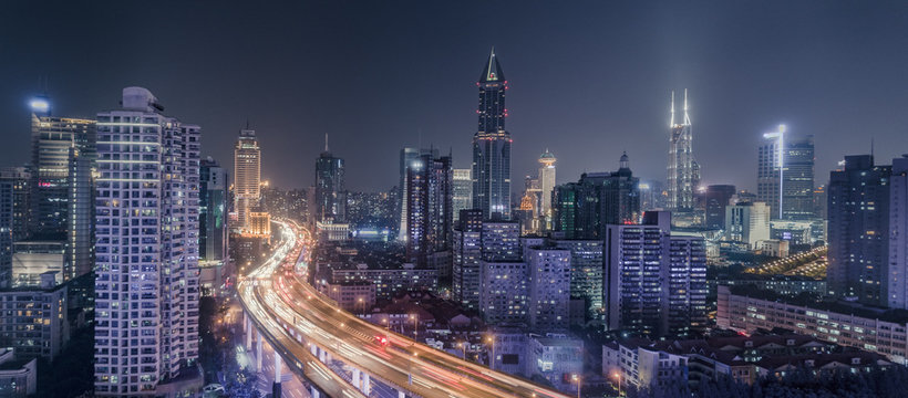 aerial view of buildings and traffic multi-level junction at night in Shanghai city