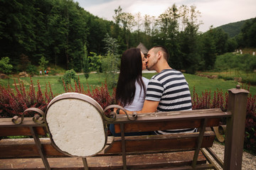 Fototapeta premium A guy and a girl enjoy each other in a romantic atmosphere and sits on the bench