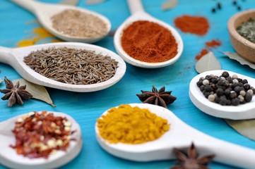 Concept of table with spices in wooden spoons on blue background, close up, selective focus