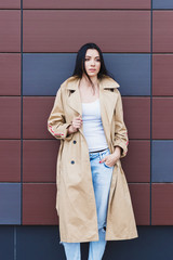 Beautiful woman in the beige coat and jeans on the street