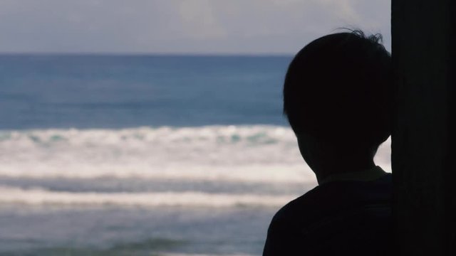 180p Slow motion shot of Silhouette of boy watching surfer riding waves